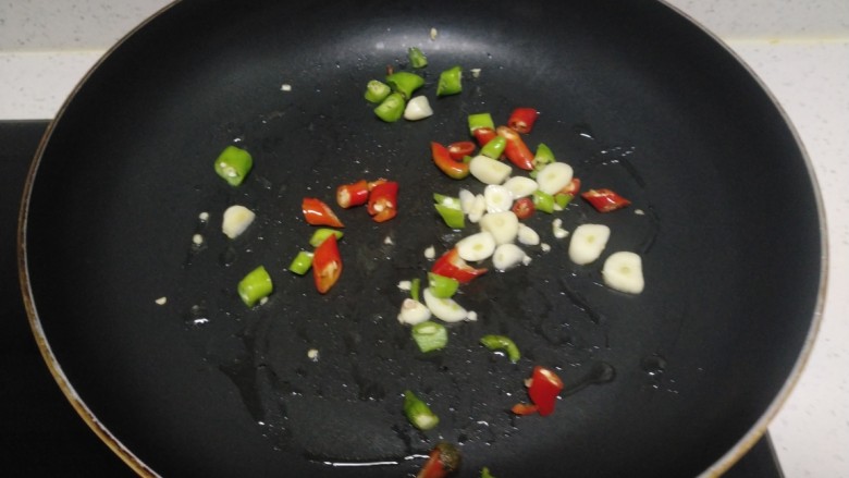 尖椒炒西红柿、丝瓜,锅中放入适量油，炒香尖椒、蒜片。
