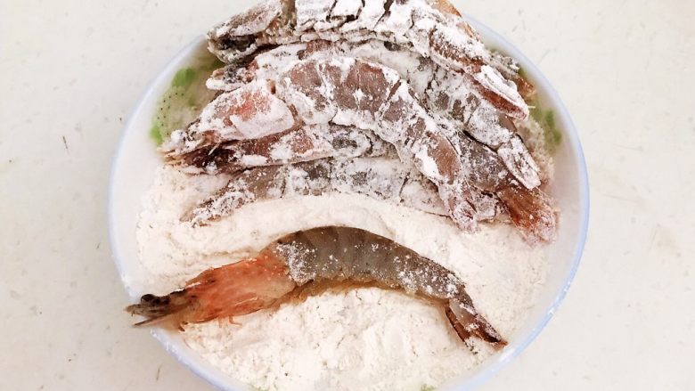 干锅基围虾,去一只腌制入味的基围虾放入面粉中打个滚，让基围虾均匀的裹上一层薄薄的面粉