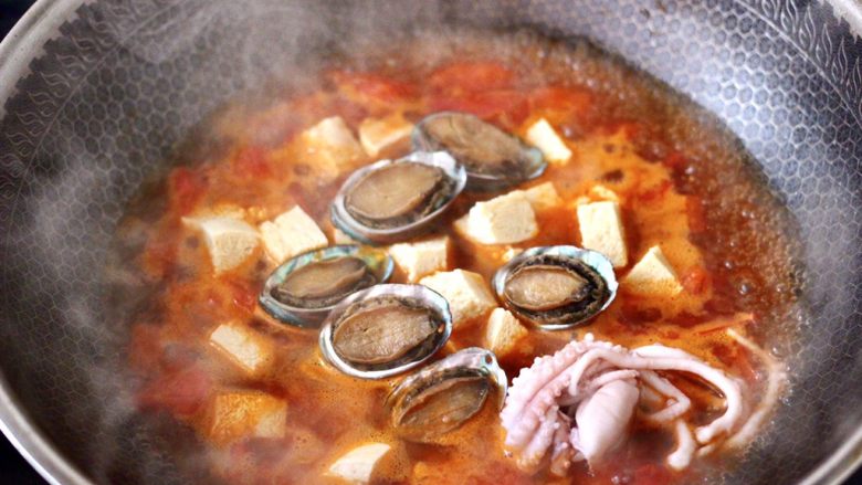 鲍鱼番茄海鲜豆腐浓汤,再放入鲍鱼和桃花蛸，大火煮沸后转中火继续煮10分钟。