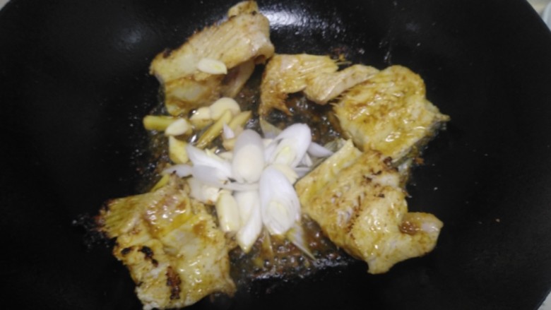 酸菜鱼,中火煎至一面金黄，翻面改小火放入葱、蒜炒香