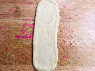 手撕面包,取一个圆形面团先将的两边轻轻地收一下，变成椭圆形，再将面团擀成一个长约30厘米的长条形，翻面