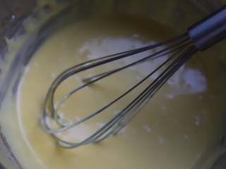 蜜豆蛋糕卷,将蛋黄与面糊混合均匀，混合的时候我们用的工具是手动打蛋器，混合的时候注意要划十字搅拌，别一直打圈，不然面糊容易起筋，混合好的面糊先放一旁静置备用。