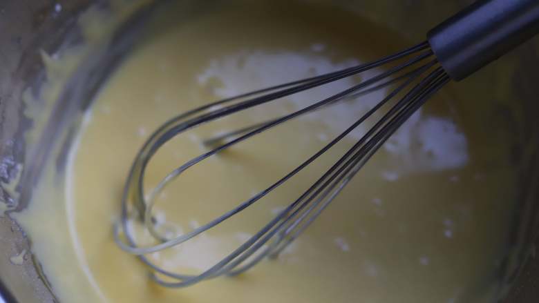 蜜豆蛋糕卷,将蛋黄与面糊混合均匀，混合的时候我们用的工具是手动打蛋器，混合的时候注意要划十字搅拌，别一直打圈，不然面糊容易起筋，混合好的面糊先放一旁静置备用。