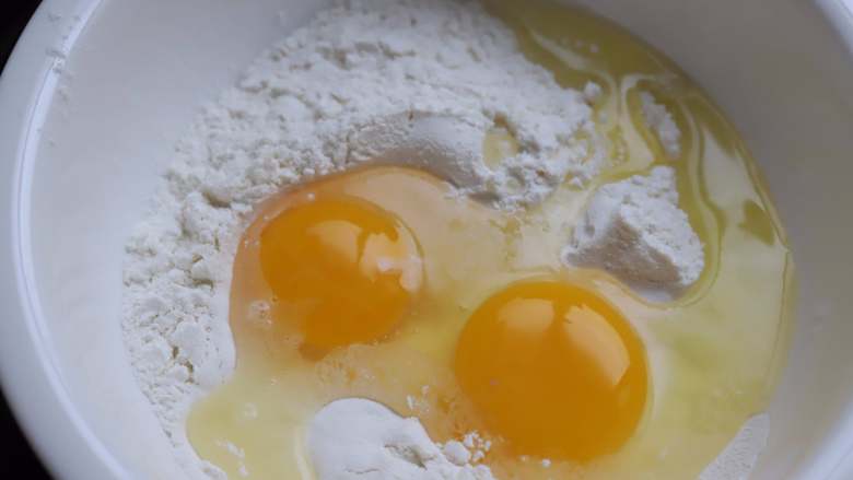 火腿鸡蛋饼,<a style='color:red;display:inline-block;' href='/shicai/ 519'>面粉</a>中打入两个鸡蛋，不放鸡蛋也可以，放一个鸡蛋也可以，鸡蛋多一些，做出来的饼吃起来就更香更软一些，特别是用普通大锅做的时候，您能发现加足了鸡蛋的饼翻面或者折叠的时候不会破，韧性好，做出来的饼颜色还好看，所以还是建议大家要加鸡蛋。