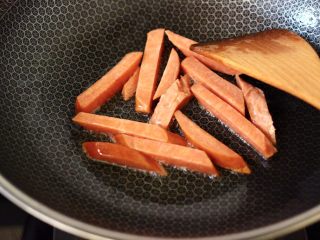辣炒火腿肠土豆条,锅烧热后，先倒入10克花生油烧热，把火腿肠用小火慢慢煎熟，这样炒出来的火腿肠口感特别棒，盛出备用。