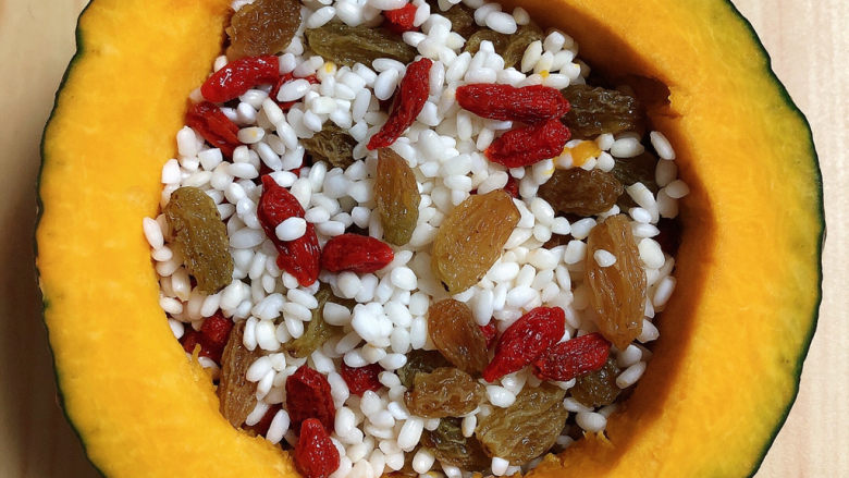 糯米南瓜盅,再放入枸杞子和葡萄干，将米粒与之搅拌均匀。