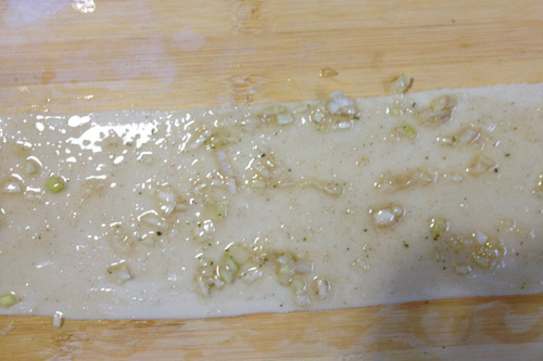 香酥葱油饼,揉好的面团分成几份，擀成大长片，稍薄些。刷上葱油。