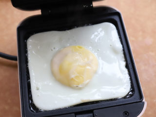 牛油果鸡蛋三明治,鸡蛋煎熟以后先取出来，然后把机器内残留的油擦去，喜欢流心鸡蛋的，煎一分钟就可以了。