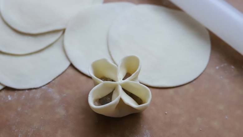 虾仁四喜饺子,如图，然后把相邻两个饺子皮分别捏紧，形成四个圆洞。