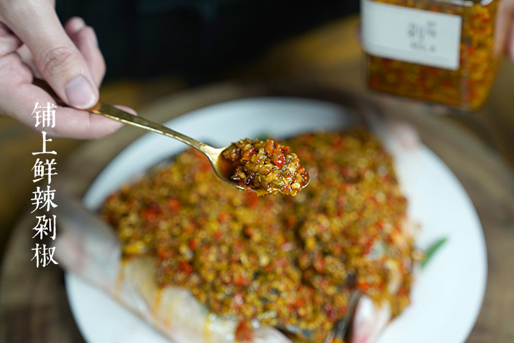 鲜辣剁椒,将三生川鲜辣剁椒均匀铺在鱼头上。
