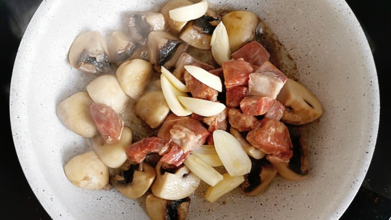 蘑菇秋葵牛肉粒,倒入腌好的牛排和蒜片，炒至牛排变色