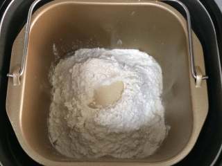 热狗面包,除黄油以外其他食材倒入面包机桶内，按先液体后粉类的顺序，然后在中间挖了洞加入酵母粉。