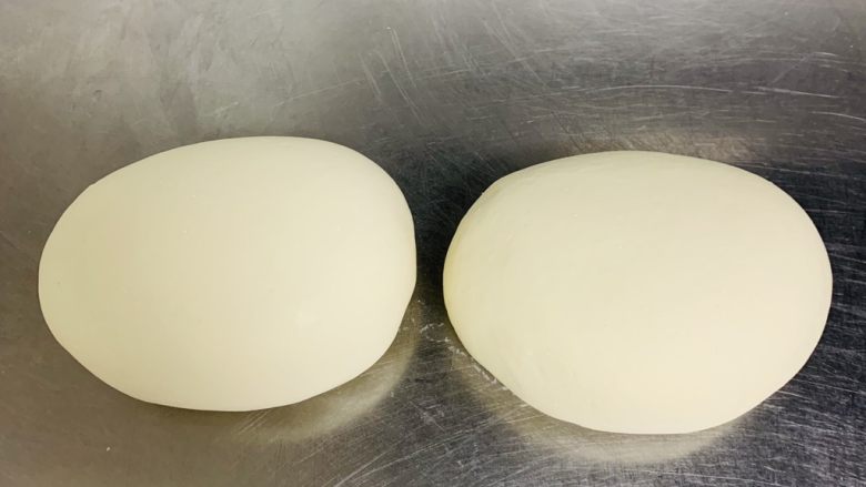 香葱千层饼,揉好的面团平均分成两份，盖上保鲜膜松弛面团5分钟。
