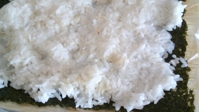 寿司,在寿司帘铺上海苔再铺上米饭，为不沾手沾点水