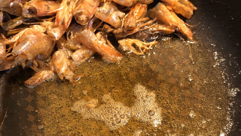 鲜虾什锦炒饭,炒至这个程度：油里有虾壳的红色，虾壳酥脆，并且可以闻到强烈的鲜味，这样虾油就炸好了。我们留住油在锅里，把虾壳捞出丢弃。