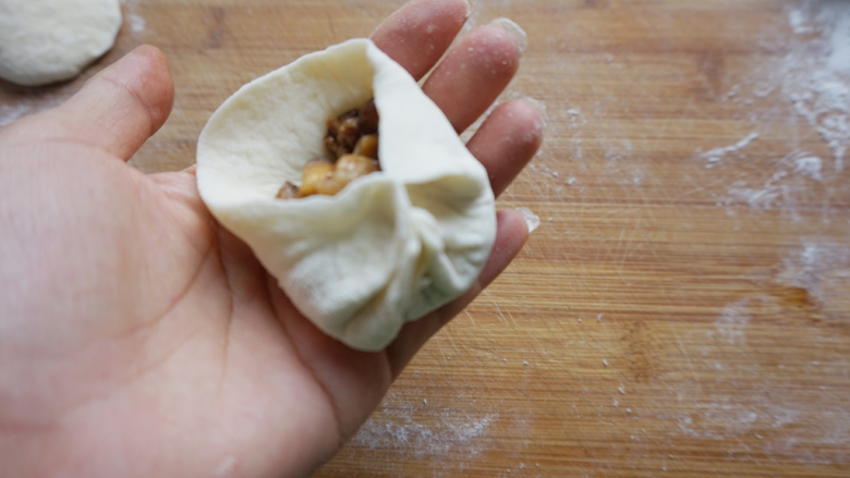 香菇卤肉丁包,包子皮放上馅料，依次捏出包子褶。
