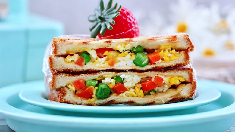 鸡蛋时蔬三明治,把做好的三明治用保鲜膜包裹起来，用刀从中间切开即可，颜值担当又营养好吃哟。