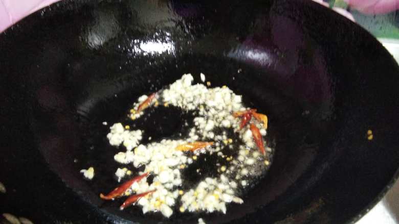 爆炒豆角,热锅凉油倒入蒜碎和辣椒丝煸出香味