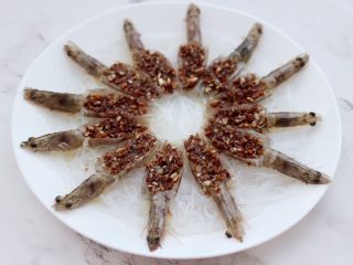 金蒜粉丝蒸海虾,把炒好的蒜末汁和料酒，浇在虾肉上面。