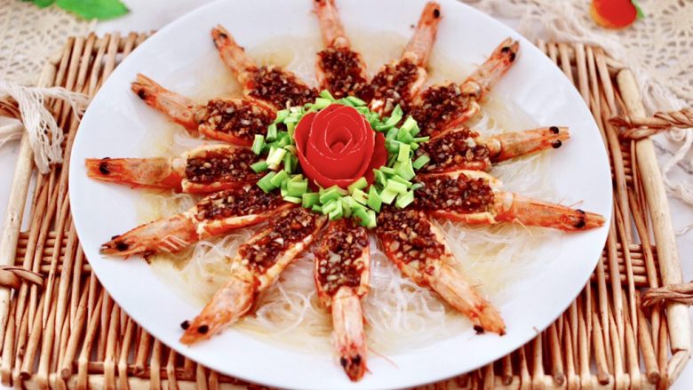 金蒜粉丝蒸海虾,把番茄小花朵放入盘子正中间，边上撒上小葱花即可。