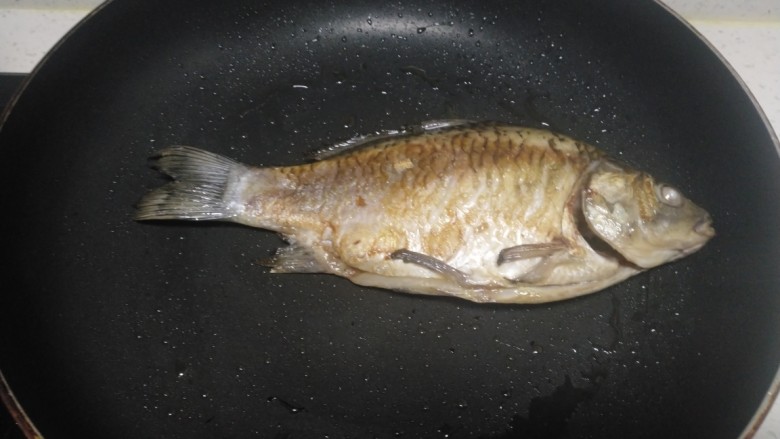 红烧鲫鱼炖冻内脂豆腐、粉皮,放入锅中煎至一面金黄