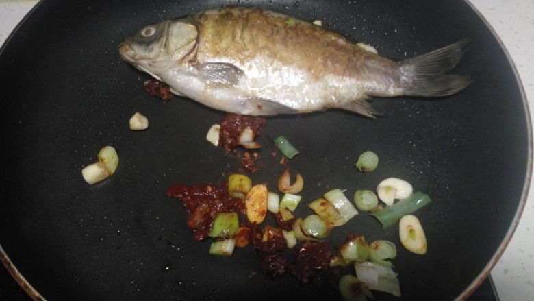 红烧鲫鱼炖冻内脂豆腐、粉皮,翻面煎至两面金黄，放入蒜、葱、豆瓣酱炒香
