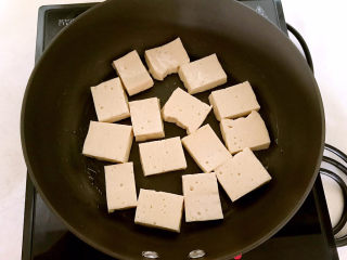明虾煲,炒锅烧热后不用放油，把豆腐片放入锅里，小火煎制