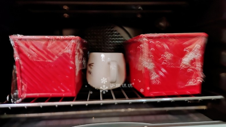 酸奶肉松面包,然后模具盖上保鲜膜放入烤箱，同时放一杯热水，关上烤箱门进行二次发酵。