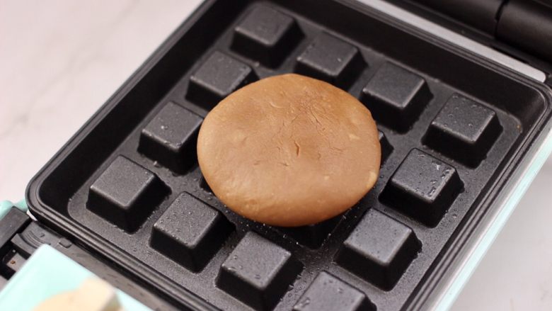 冬至美食～咖啡红薯华夫饼,华夫饼机器提前预热后，用刷子在机器上刷少许食用油，把做好的面团摁扁放入烤盘上。