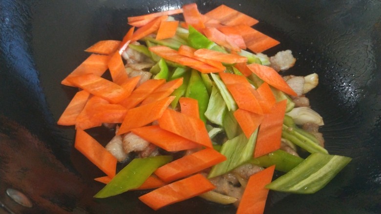 冬至美食+香菇炒肉,倒入胡萝卜尖椒炒均匀。