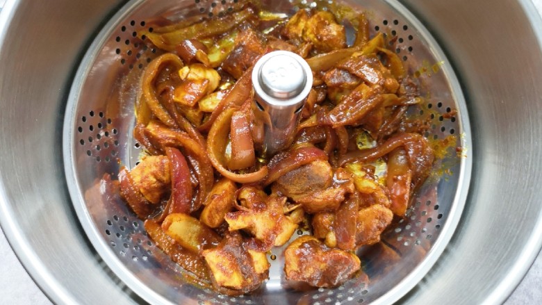 冬至美食  咖喱丸子火锅,将炒好的洋葱和鸡腿块一起放进升降火锅的提篮里，加水没过提篮。
