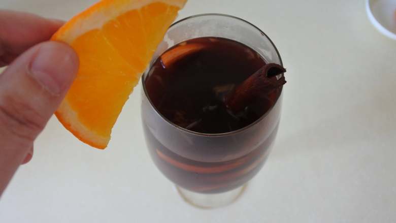 冬至美食-热红酒, 其余的酒过滤掉果渣，倒入酒杯中。放上肉桂棒，杯口插一片橙子点缀