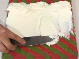 圣诞蛋糕卷,台面垫油纸，蛋糕卷正面朝上，将末端斜切一下，抹上打发好的蛋糕霜，