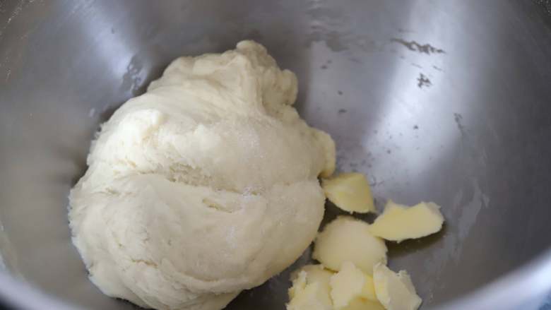 草莓酥粒面包,启动厨师机，先低速将面团混合均匀，再转高速将面团搅打至均匀的状态，然后加入盐和黄油，继续用高速搅打。