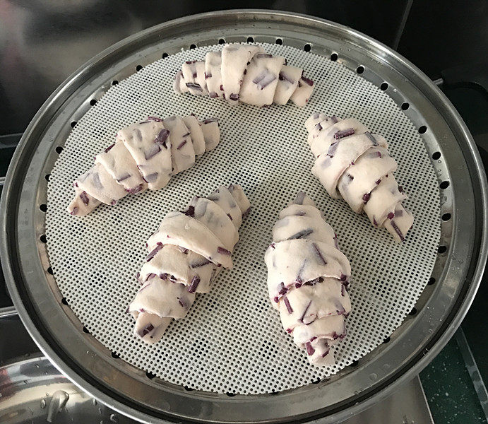 紫薯小馒头,均匀地摆在蒸屉上，锅中加少许温水，加盖二次饧发20分钟左右