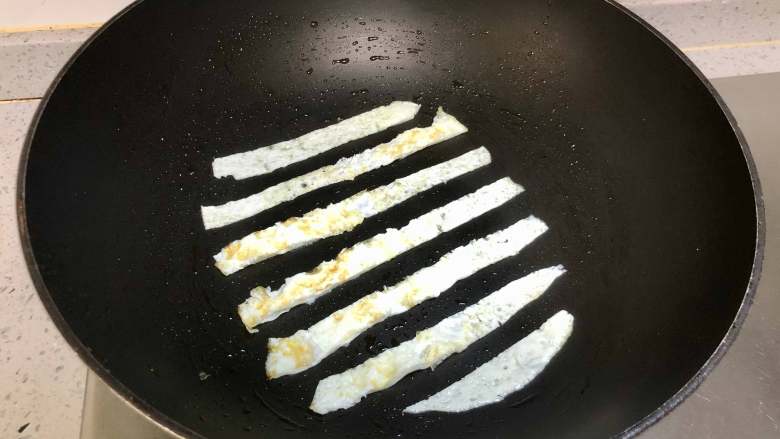 蛋包饭也可以萌萌哒，糖果的造型超吸睛！,锅里再刷一层油，把蛋清层出切成条，如图每条间隔一样的宽度的放入锅中。