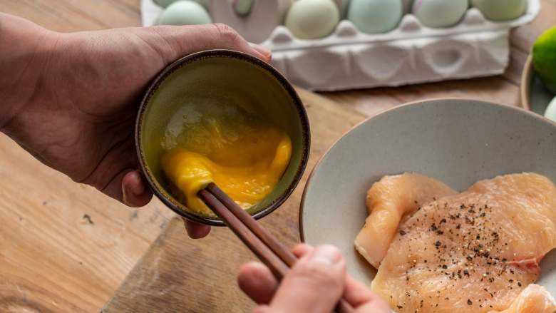 诗仙范闲惊艳的~酸辣蜜恋酱鸡排,将鸡蛋磕入碗中打散。