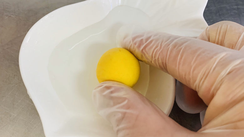 南瓜芝麻球,在水碗里表面少少的粘上一点水，这样做让芝麻更好地贴合在南瓜球上。
