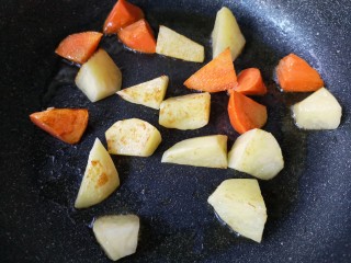 土豆牛腩煲,锅中少量油，下土豆和胡萝卜块煎至表面微焦后盛出备用。