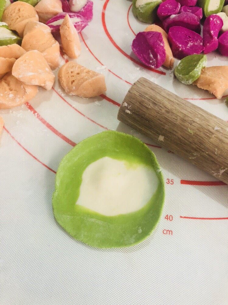 彩色水饺,每个都擀成近圆形薄片。记得撒点面粉在面皮上，避免互相粘连。