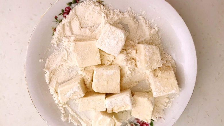  糖醋焦熘豆腐,把豆腐块放在面粉中打个滚，让豆腐均匀的蘸上一层薄薄的面粉