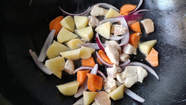 咖喱鸡肉土豆,大火翻炒至鸡丁变白后下入土豆胡萝卜和洋葱继续翻炒一下。