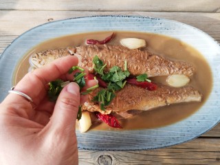 酱焖黄花鱼,将烧好的鱼沿锅边滑入盘中（黄花鱼的烹饪与其他鱼相比，容易熟，但也容易烂，中国人是讲究全鱼的），撒上香菜末。