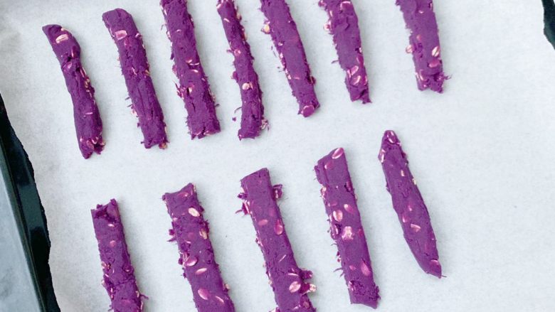 紫薯燕麦磨牙棒,切好的紫薯条放入烤盘中。烤箱预热150度5分钟然后放入烤箱中层上下火150度20分钟左右（烤箱的温度根据自家烤箱而定的哦）
