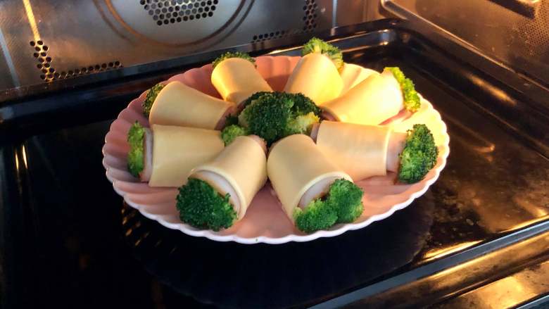 “花”开富贵——焗烤西兰花培根卷,烤箱预热180度，把西兰花培根卷放入烤箱焗烤10分钟即可。