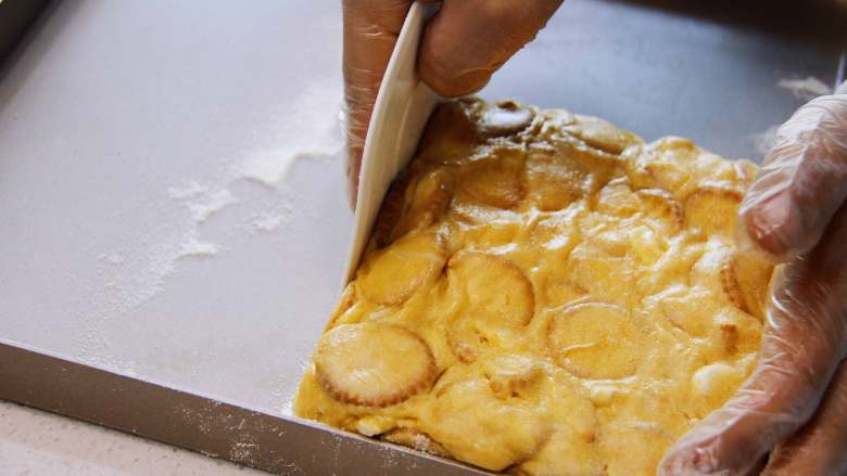 咸蛋黄雪花酥, 将混合好的雪花酥放入不粘烤盘中，按压紧实，并用刮板整理成方正的状态，减少边角料。