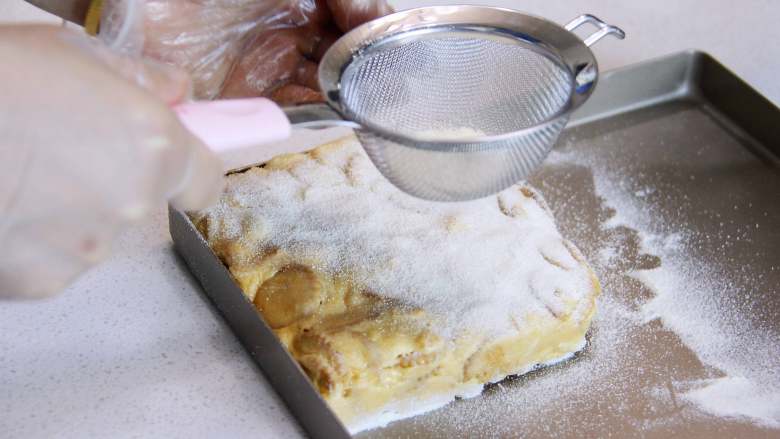 咸蛋黄雪花酥,在雪花酥还有温度时在表面筛奶粉，翻面稍整理同样筛奶粉。