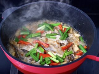 鲳鱼烧冻豆腐,放入红辣椒条，大火煮沸后，看见红椒变色断生，撒上韭菜段。