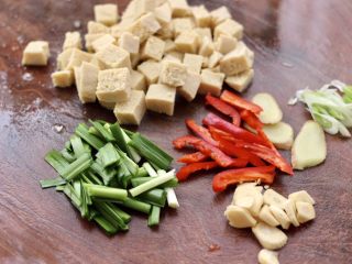 鲳鱼烧冻豆腐,把冻豆腐洗净用刀切成小方块，韭菜切段，红椒去籽切条，大蒜去皮切片，姜切片，葱切碎。