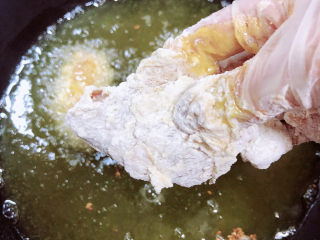 香酥炸鸡翅,将裹好面粉的鸡翅逐一放入油锅中。